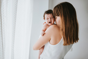 baby cries in her mother's arms - family