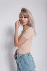 Fashion model of a glamorous young blonde woman in stylish blue jeans in a trendy shirt with a...