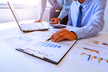Two business man people working analyzing and calculate summary of cost from document chart and graph with calculator at office, Accounting and finance in the office.