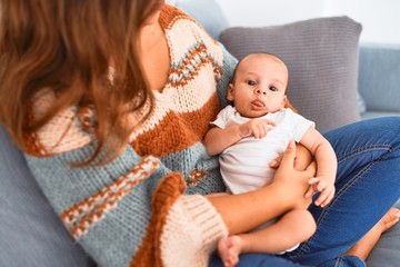 Young beautiful woman and her baby on the sofa at home. Newborn and mother relaxing and resting comfortable