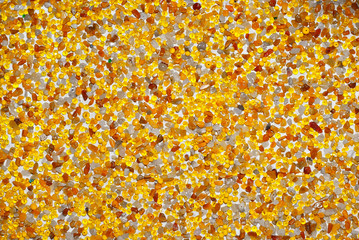Texture of various jewels on a white background. Yellow, brown and orange stones. Beads and necklaces are glued to the wall.