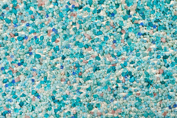 Texture of various jewels on a white background. Blue, purple, pink and cyan stones. Beads and necklaces are glued to the wall.