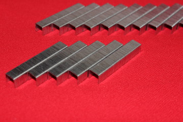  Staples for a stapler are exposed on a red background. Staples isolated on red background