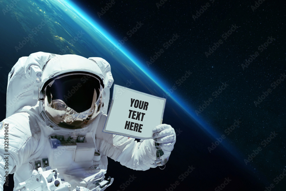 Poster Spaceman in open space shows a card with your text here on the background of planet earth. Astronaut with advertising message