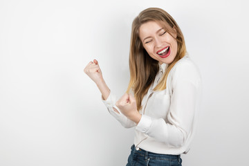 young beatuiful blond woman standing in winning position looking happy on isolated white...