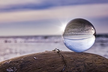 Lensball as the subject on a piece of driftwood during a beautiful sunset at the beach