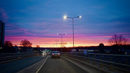Fototapeta na wymiar Beautiful colorful sunset in the city. Cars driving on the road during dawn.