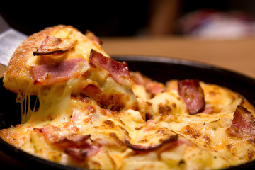 Hot pizza slice with melting cheese on a  table in restaurant pizza Italian food.