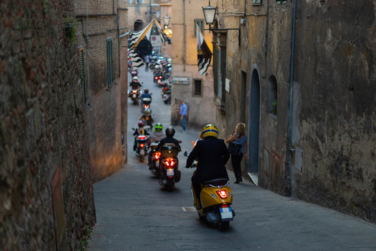 A line of scooters on a narrow street in Siena, Italy.