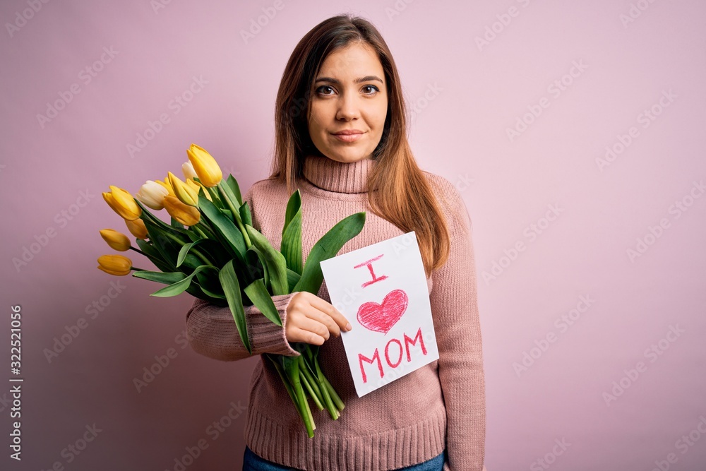 Canvas Prints Beautiful woman holding paper with love mom message and tulips celebrating mothers day with a confident expression on smart face thinking serious