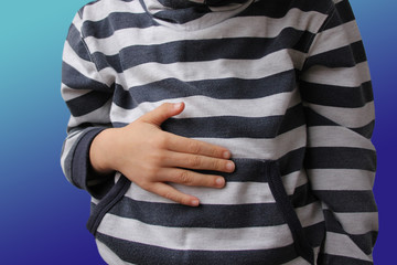 boy, child in a striped sweater holds his stomach by his hand, pain concept