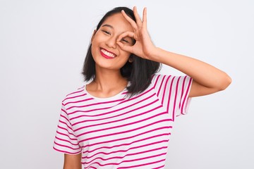Fototapeta na wymiar Young chinese woman wearing striped t-shirt standing over isolated white background doing ok gesture with hand smiling, eye looking through fingers with happy face.