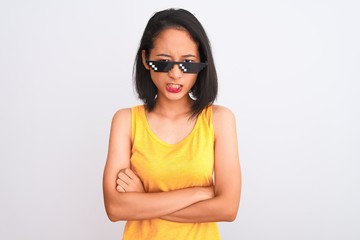 Young beautiful chinese woman wearing thug life sunglasses over isolated white background skeptic and nervous, disapproving expression on face with crossed arms. Negative person.