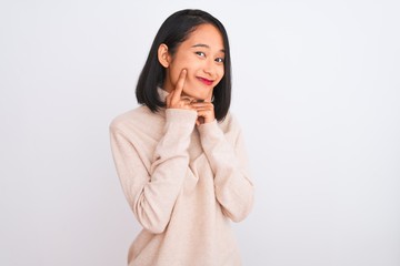 Young chinese woman wearing turtleneck sweater standing over isolated white background Smiling with open mouth, fingers pointing and forcing cheerful smile