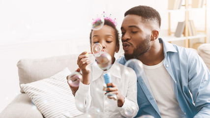 Handsome man spending time with daughter, blowing soap bubbles together