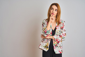 Young caucasian business woman wearing spring floral jacket suit over isolated background with hand on chin thinking about question, pensive expression. Smiling with thoughtful face. Doubt concept.