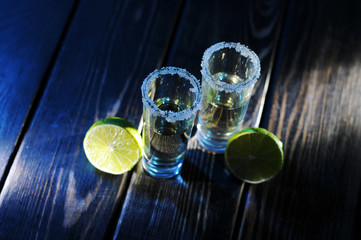 Alcoholic drink concept. Mexican tequila with lime and salt on rustic wood background. space for...