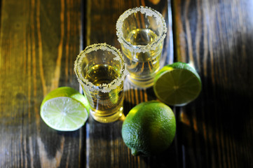 Alcoholic drink concept. Mexican tequila with lime and salt on rustic wood background. space for...