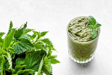 Detox juice or green smoothie with leaves of nettle blended in a glass