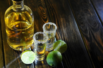 Alcoholic drink concept. Mexican tequila with lime and salt on rustic wood background. space for...