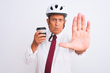 Senior businessman wearing bike helmet drinking coffee over isolated white background with open hand doing stop sign with serious and confident expression, defense gesture