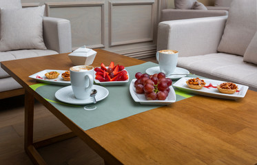 Desert table with sweeties, cappuccino and fruits