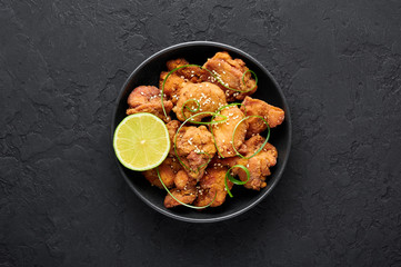 Chicken Karaage in black bowl at dark slate background. Karaage is traditional japanese cuisine dish with deep fried marinated chicken. Copy space. Top view