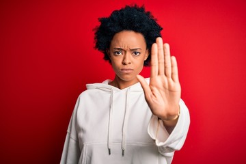 Fototapeta na wymiar Young beautiful African American afro sportswoman with curly hair wearing sportswear doing stop sing with palm of the hand. Warning expression with negative and serious gesture on the face.