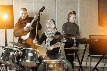 Music band with cheerful girl drummer rehearsing