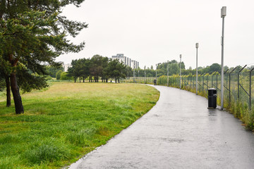 Fototapeta na wymiar Path lined with a fence and street lights in a public park