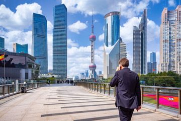 Business man walking and use smartphone in shanghai city