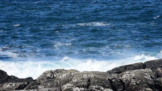 Big wave crashing into rocks on rocky seashore