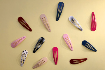 Colorful trendy hair clips on bright yellow background. Top view.