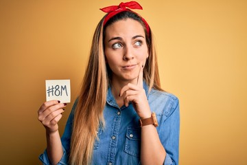 Beautiful woman with blue eyes celebrating 8th march womens day holding reminder paper serious face...