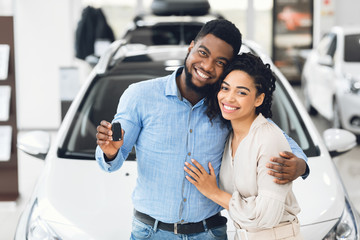 African American Couple Showing Car Key Standing In Automobile Showroom
