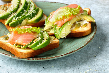 Toast with avocado and salmon on a plate on the table close-up.