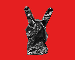 Black rubber glove showing two fingers Isolate on red background. Gesture that rocks or horns
