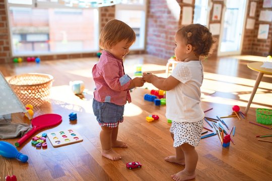 Adorable toddlers playing around lots of toys at kindergarten
