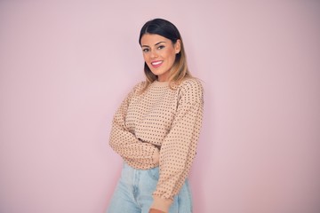 Obraz premium Young beautiful woman wearing fashionable clothes smiling happy and confident. Standing with smile on face over isolated pink background
