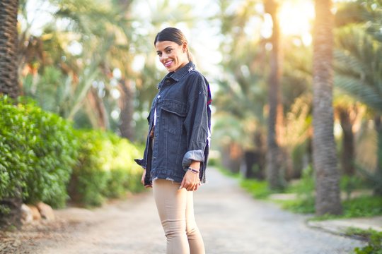 Young beautiful woman wearing denim jacket smiling happy and confident. Standing with smile on face at the town park
