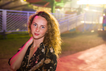 Obraz premium Red millennial teenager tourist enjoy having fun at luna park, elegantly dressed,illuminated by neon light, she's lovely girl.