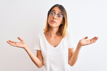 Beautiful redhead woman wearing glasses over isolated background clueless and confused expression...