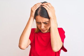 Beautiful redhead woman wearing casual red t-shirt over isolated background suffering from headache...