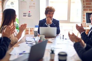 Group of business workers smiling happy and confident in a meeting. Working together looking at presentation using board and laptop applauding at the office.