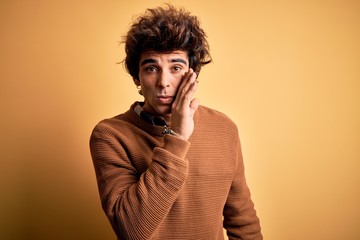 Fototapeta na wymiar Young handsome man wearing casual shirt and sweater over isolated yellow background hand on mouth telling secret rumor, whispering malicious talk conversation