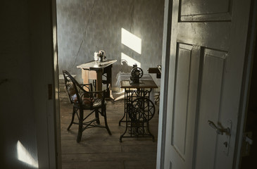 Open door in front of an antique workplace room with sewing machines