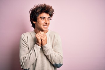 Fototapeta na wymiar Young handsome man wearing casual t-shirt standing over isolated pink background laughing nervous and excited with hands on chin looking to the side