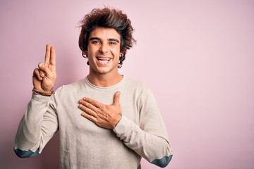Young handsome man wearing casual t-shirt standing over isolated pink background smiling swearing with hand on chest and fingers up, making a loyalty promise oath