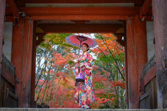 Woman Holding Retro Umbrella In Old Fashion Style Traditional Kimono, Stand Alone In The Middle Of Park Of The Village Garden In Autumn, Travel And Visit Japan On Incoming Sport Event