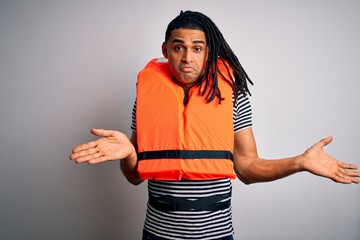 Young african american afro man with dreadlocks wearing orange lifejacket clueless and confused...